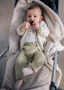 Baby wearing green knit pants, white cardigan, and white bodysuit in stroller