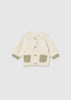 Cream knit baby cardigan with sage green pockets, cuffs, and wooden buttons